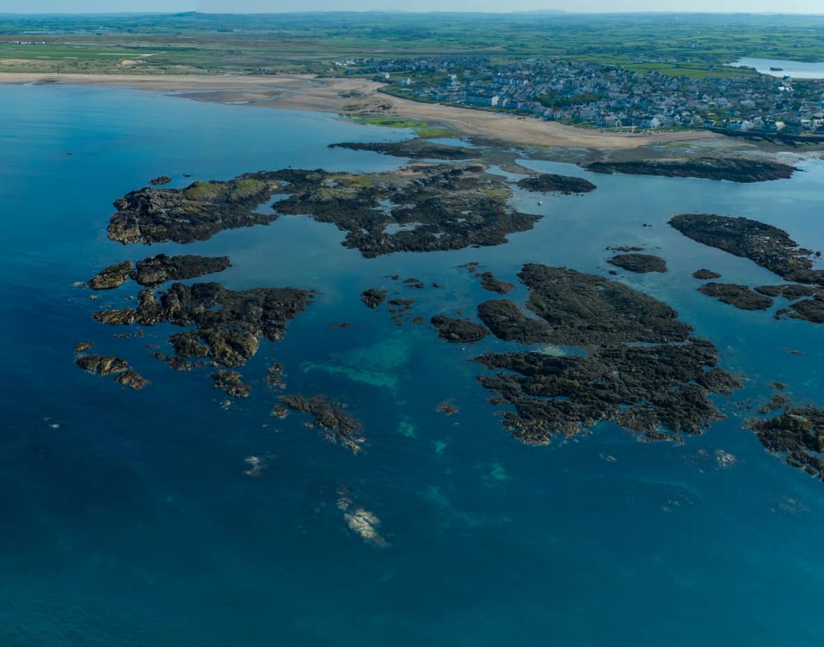 drone captured image of rhosneigr from the air with blue water in the foreground