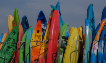 Kayaks in all the colours of the rainbow standing in a row.dng