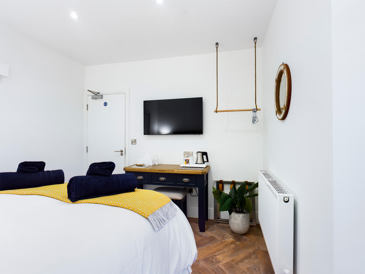 Room Two - full room image showing bed, television, radiator and dressing table