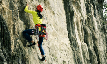 female rock climber climbing on mountain cliff