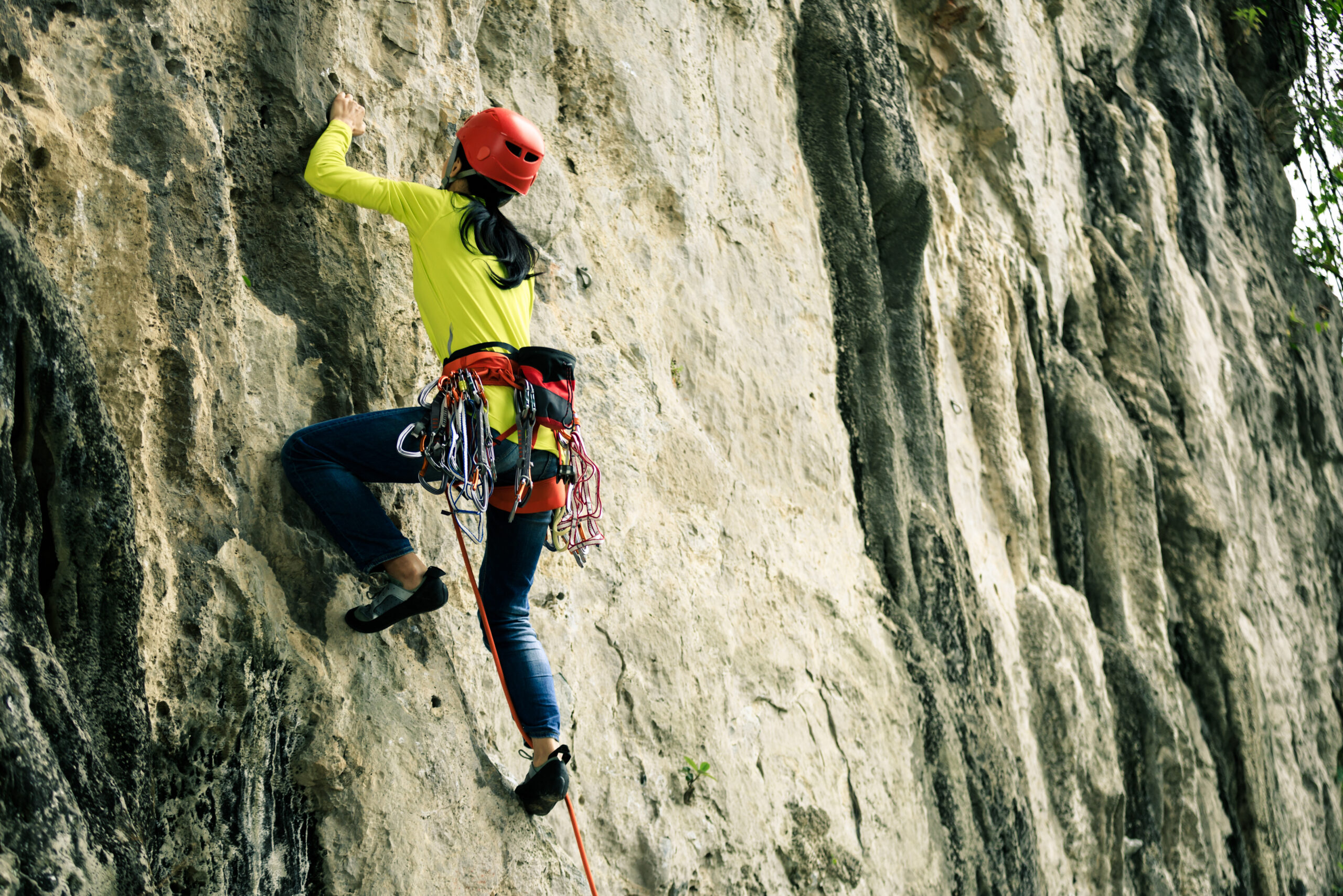 female rock climber climbing on mountain cliff