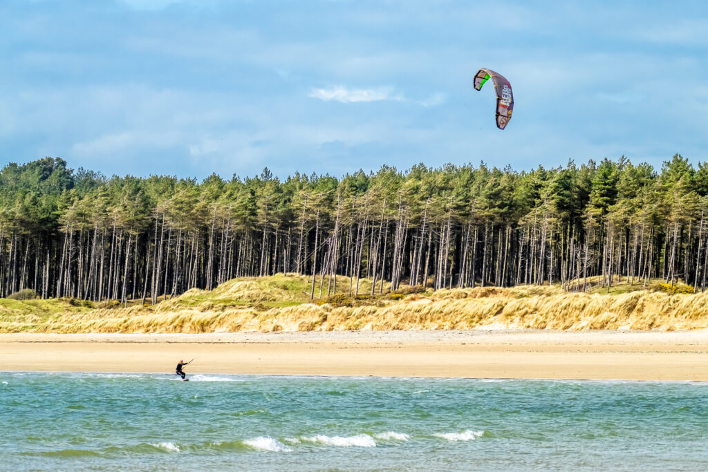 NEWBOROUGH / WALES - APRIL 26 2018 : Kite flyer surfing at Newborough beach - Wales - United Kingdom