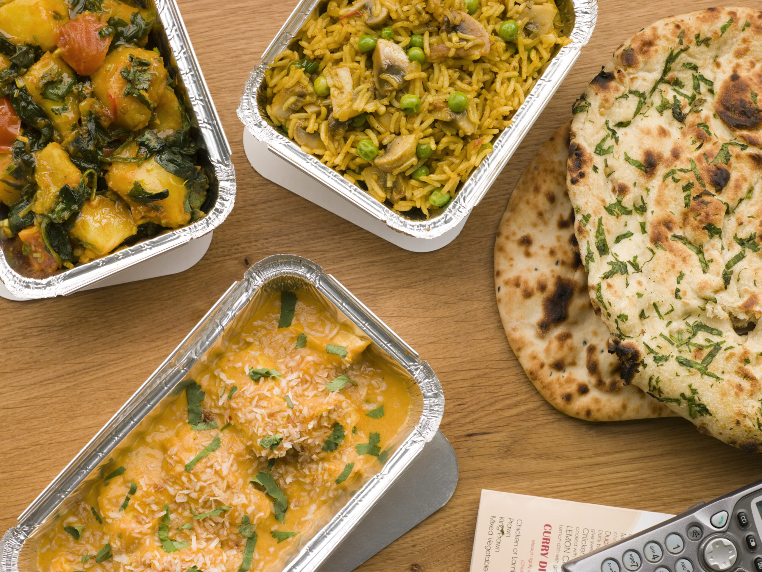 Chicken Korma, Sag Aloo, Mushroom Pilau And Naan Bread On Table