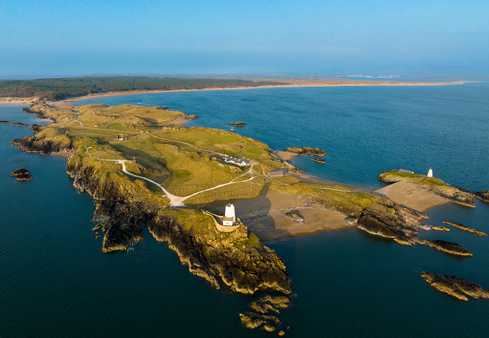 Ynys Llanddwyn is a tidal island; it remains attached to the mainland except at high tide. It provides views of Snowdonia and the Llŷn Peninsula. Tŵr Mawr lighthouse marks the western entrance to the Menai Strait.