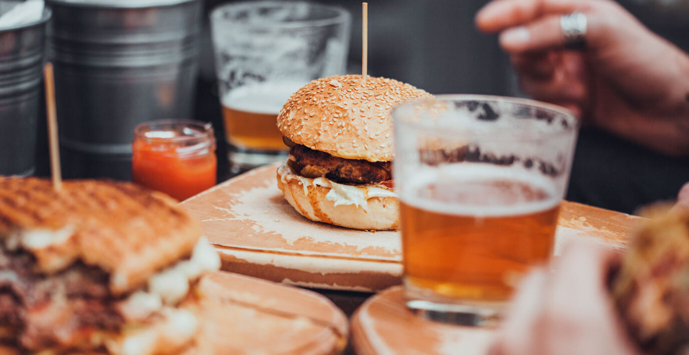 Delicious Pub Food. Burgers And Glasses Of Beer On Wooden Plates