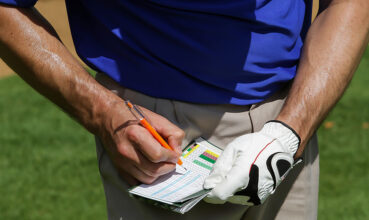 Cropped arms and hands of Caucasian Golfer keeping score on scorecard