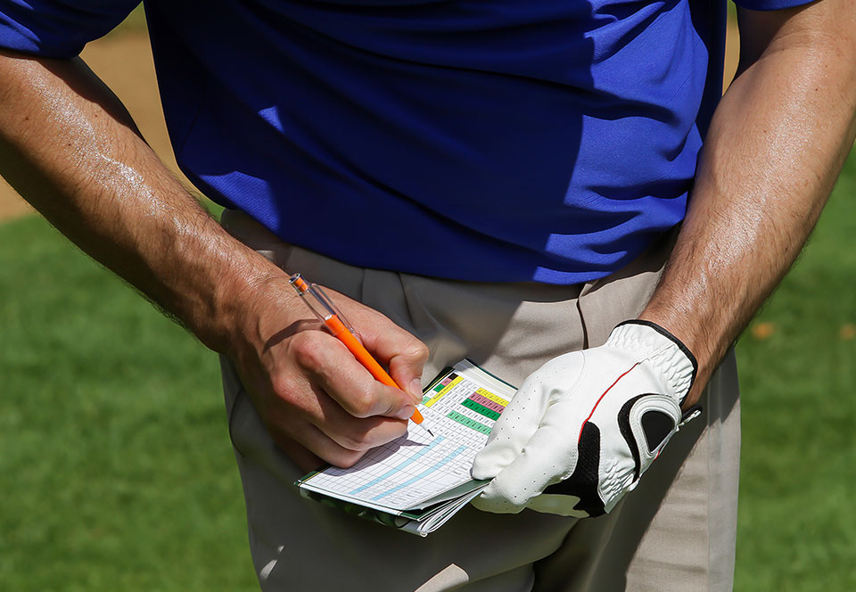 Cropped arms and hands of Caucasian Golfer keeping score on scorecard