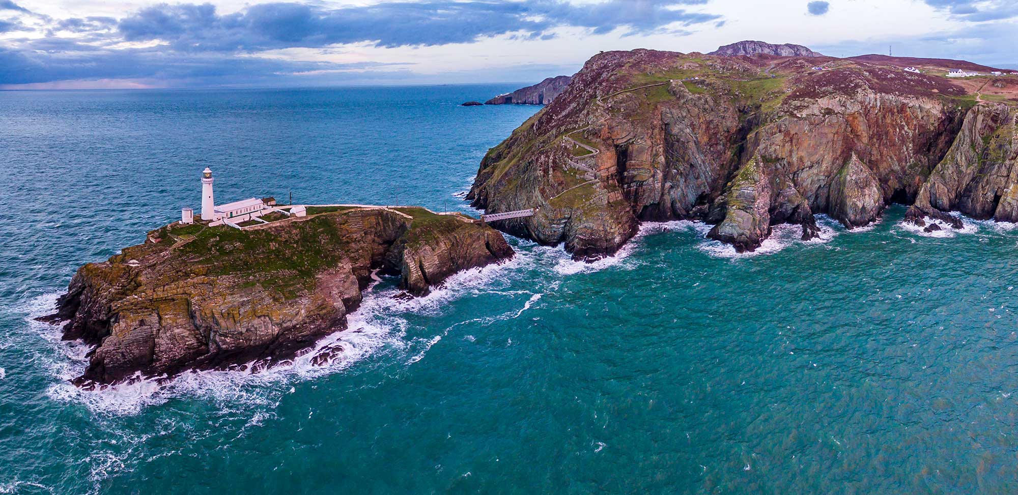 Aerial view of South Stack with lighthouse during sunset.