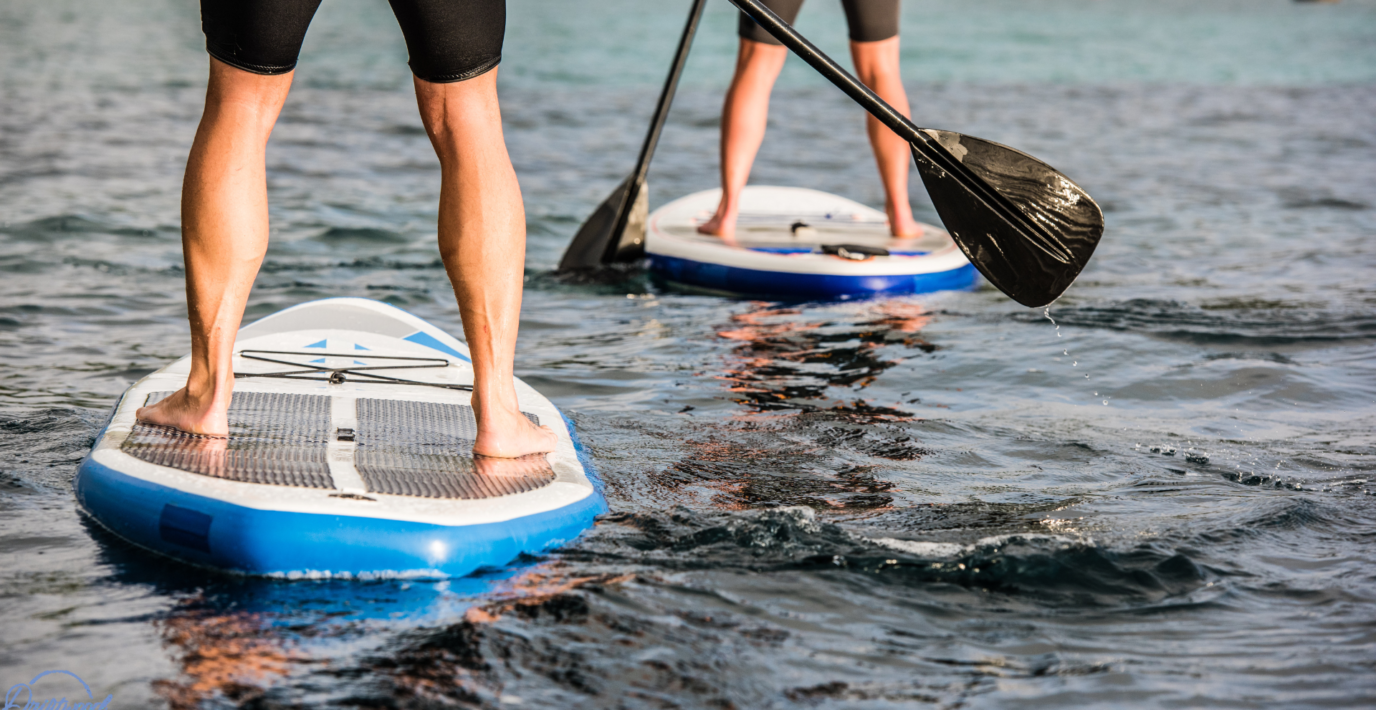 2 Paddleboards with the lower legs of men from behind on the water in North Wales