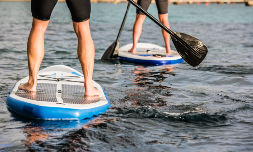 2 Paddleboards with the lower legs of men from behind on the water in North Wales